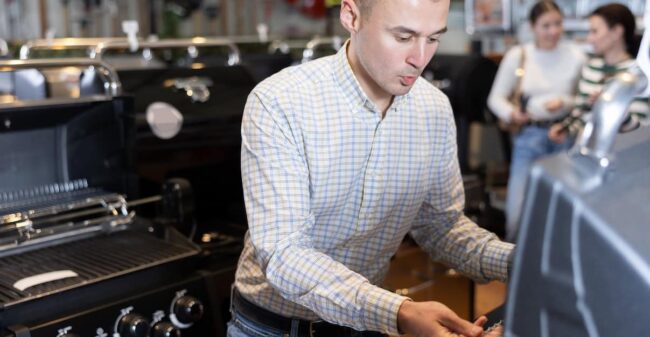 Satisfied customer in hypermarket chooses a barbecue grill for his backyard Buying a Grill Local